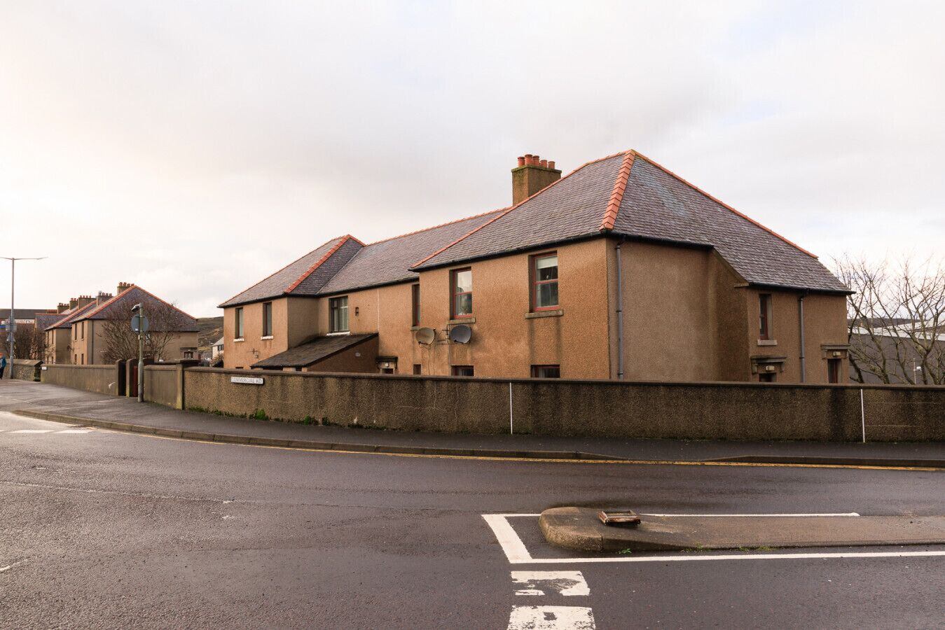 A residential street with houses, a clear road, and a pedestrian crossing.