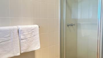Een douche, handdoeken, zeep, toiletpapier