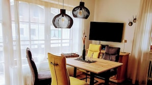 Uma sala de jantar com uma mesa de madeira, cadeiras amarelas e luminárias pendentes pretas.