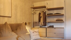 Quarto com cama, mesa de cabeceira, guarda-roupa e prateleira na parede.