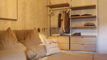 Ein Schlafzimmer mit einem Bett, einem Nachttisch, einem Kleiderschrank und einem an der Wand befestigten Regal.