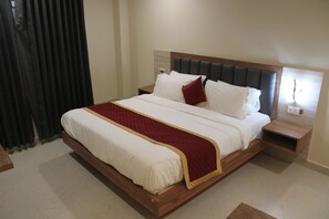 A large bed with a wooden frame, a red and white bedspread, and two bedside tables. - Siva Subramaniyar Residency (Tiruvannamalai)