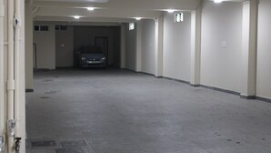 Een parkeergarage met een auto in de verte, betonvloeren en witte muren.
