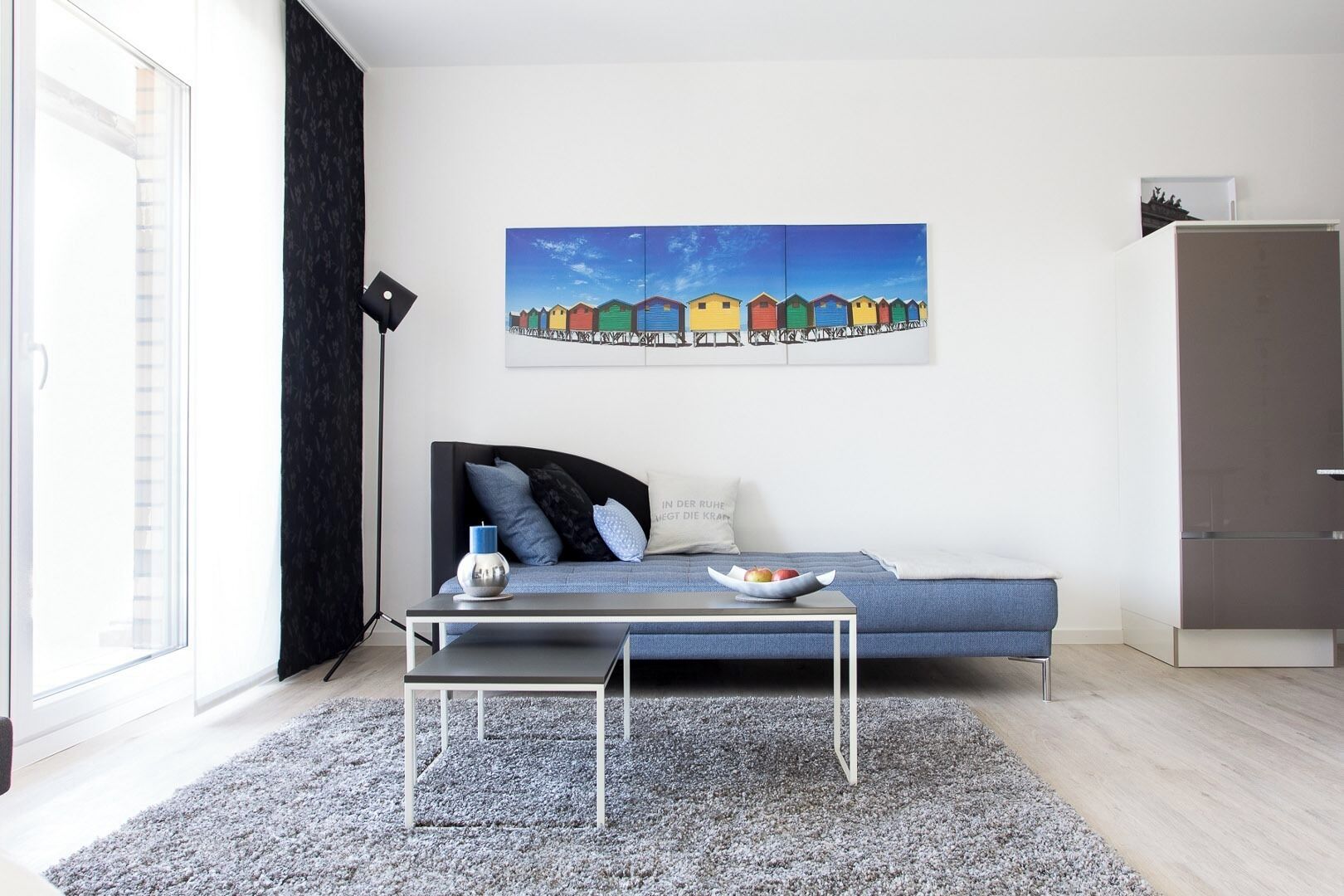 Un salon moderne avec un canapé, une table basse, un tableau et une armoire.