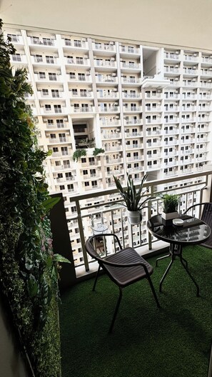 A balcony with artificial grass, two wicker chairs, a small table, and a potted plant. - Cozy LUZZO HOME 1-br luxury condo in  Kapitolyo pasig area 2mins away from BGC (Pasig)