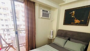 A hotel room with a bed, a painting, an air conditioning unit, and a view of the outside balcony. - Cozy LUZZO HOME 1-br luxury condo in  Kapitolyo pasig area 2mins away from BGC (Pasig)