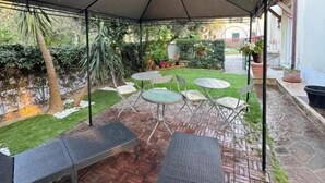 A covered patio area with a brick floor, metal chairs, and tables. - B&B Topaze (Sirmione)