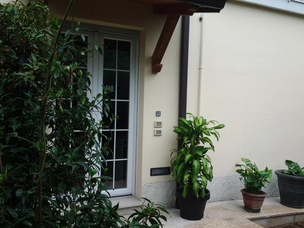 A building exterior with a door, potted plants, and a wall-mounted electrical box.