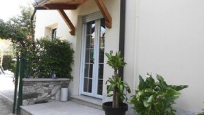 A house with a stone wall, a wooden porch, and potted plants. - B&B Topaze (Sirmione)