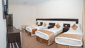 A hotel room with four single beds, a desk, and a television. - Jawharat Al Diyar - 1 (Makkah)