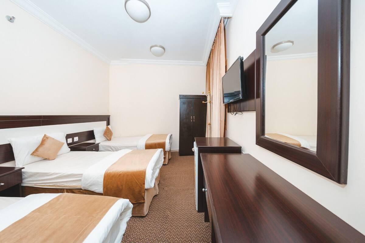 A hotel room with two beds, a wooden dresser, a flat-screen TV, and a door.