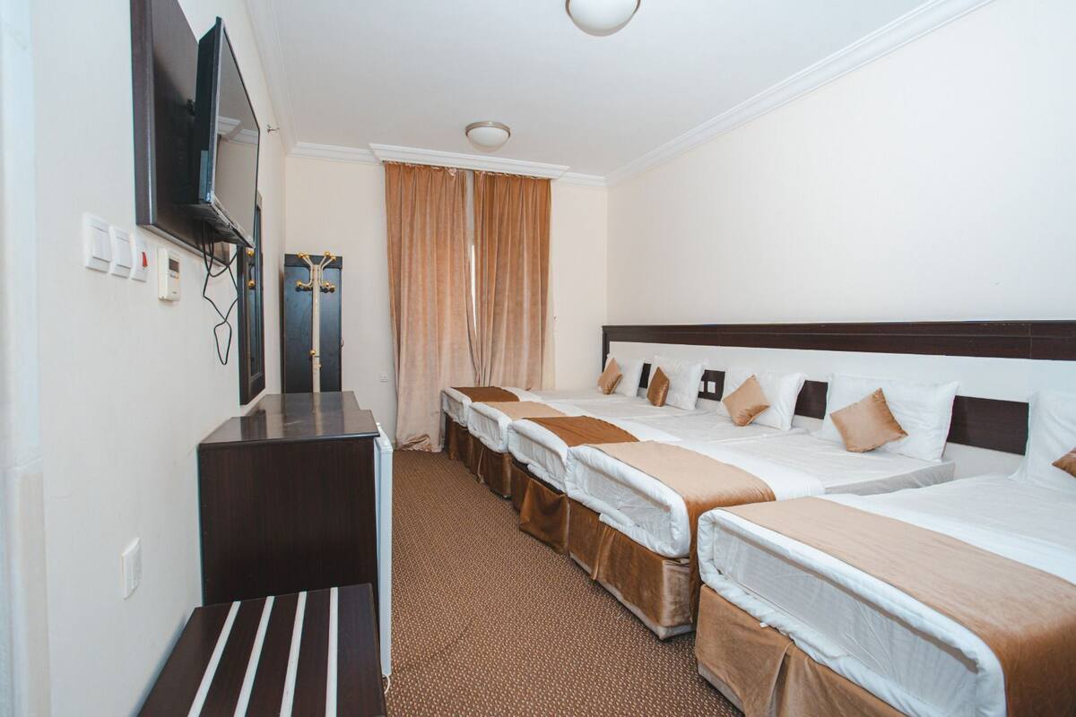 A hotel room with two beds, a desk, a television, and a bathroom door.
