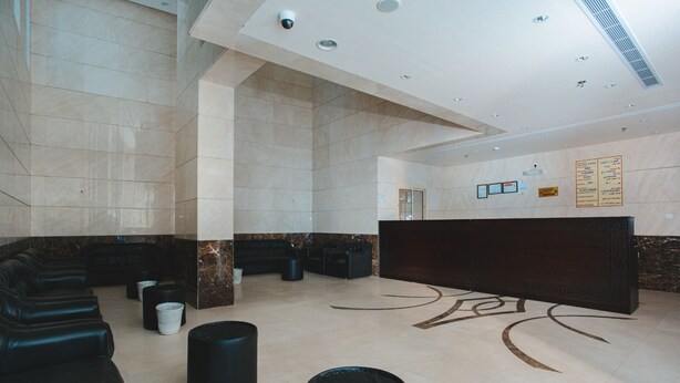 A spacious lobby with a reception desk, seating area, and a patterned floor. - Jawharat Al Diyar - 1 (Makkah)