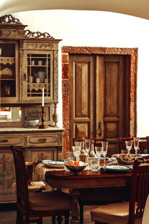 A dining area with a wooden table set for a meal, surrounded by chairs. - Historical Villa Santa Croce (Santorini)