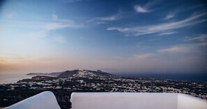 Une ville côtière au crépuscule, avec une montagne en arrière-plan et une vue sur la mer.