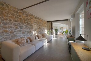 Un salón moderno con pared de piedra, sofá blanco y mesita de madera.