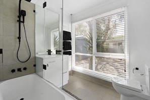 A modern bathroom with a bathtub, a toilet, and a shower.