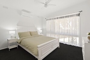A bedroom with a bed, bedside tables, a ceiling fan, and sheer curtains. - Ohana Hale, Safety Beach. (Safety Beach)