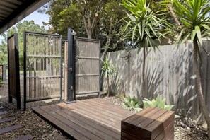 A wooden deck with a metal gate, surrounded by a wooden fence and greenery. - Ohana Hale, Safety Beach. (Safety Beach)