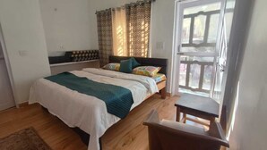 Une chambre à coucher avec un lit, une chaise, une petite table, une fenêtre avec des rideaux et une porte.