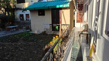 Un patio con un edificio de techo verde, una mesa pequeña y una silla.