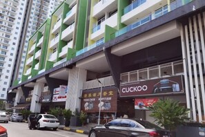 Un immeuble à plusieurs étages dont le rez-de-chaussée est occupé par des commerces, notamment un magasin Cuckoo et un restaurant Teco Chen.