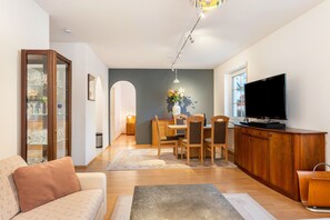 A living room with a sofa, a coffee table, a TV, a dining area with chairs and a table, and a cabinet. - Apartment "Residenz Mälscher Aue" with Balcony and Wi-Fi (Malsch)