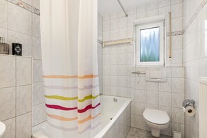Un baño con bañera, inodoro y ventana.