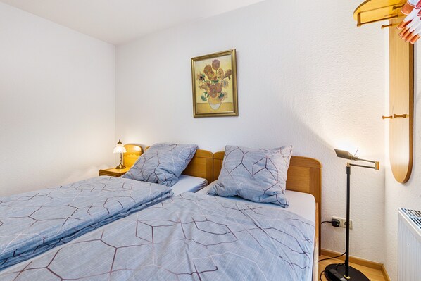 A bedroom with a bed, bedside table, lamp, and a painting on the wall. - Apartment "Residenz Mälscher Aue" with Balcony and Wi-Fi (Malsch)
