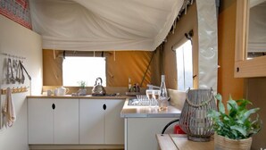 A compact kitchen with white cabinets, a striped rug, and a small window. - Woodpecker at Kittisford Barton, Somerset with hot tub (Wellington)