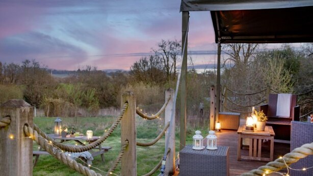 An outdoor seating area with rope barriers, string lights, and lanterns. - Woodpecker at Kittisford Barton, Somerset with hot tub (Wellington)