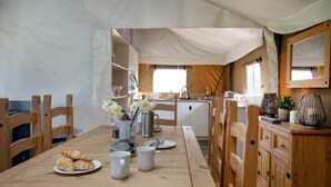 A cozy kitchen with wooden furniture, a dining table set with plates and cups, and a window providing natural light. - Woodpecker at Kittisford Barton, Somerset with hot tub (Wellington)