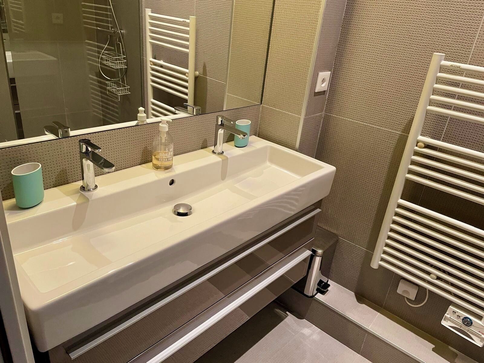 Une salle de bain moderne avec un grand lavabo, un miroir et un porte-serviettes.