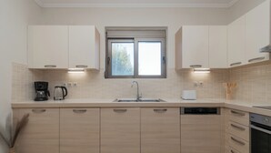 Ett modernt kök med ljusa träskåp, en inbyggd diskmaskin och ett fönster ovanför diskbänken.