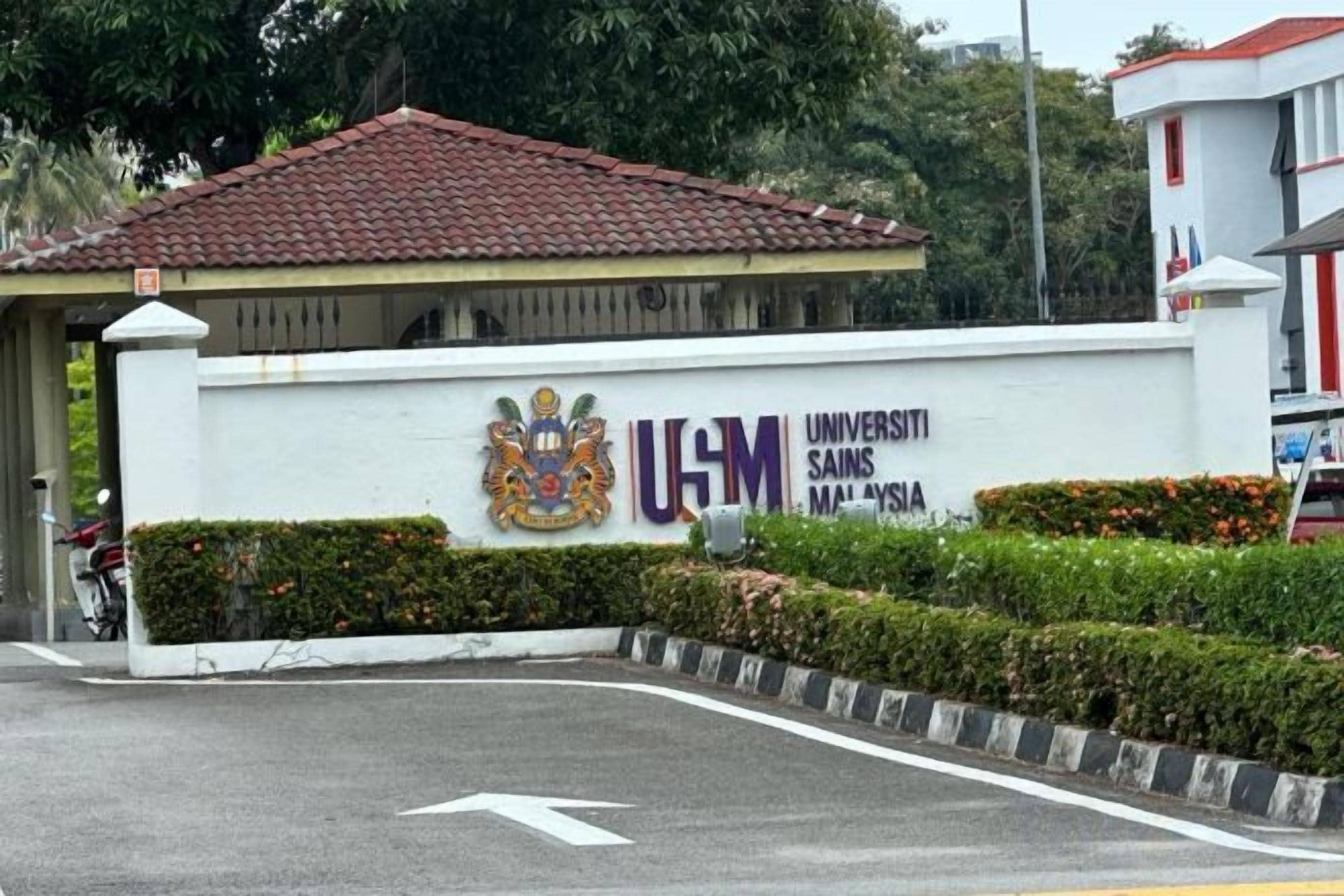 A building with a sign reading 'Universiti Sains Malaysia' and a red-tiled roof.