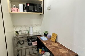 A compact kitchen with a microwave, kettle, and kettle on the countertop. - The CEO SuiteZ2 By Homey Planet (Bayan Lepas)