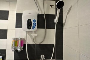 Un baño con ducha, un panel de control y tres botellas de jabón.