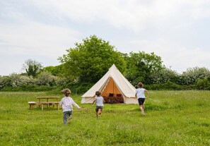 Een tent in een grasveld met een picknicktafel in de buurt.