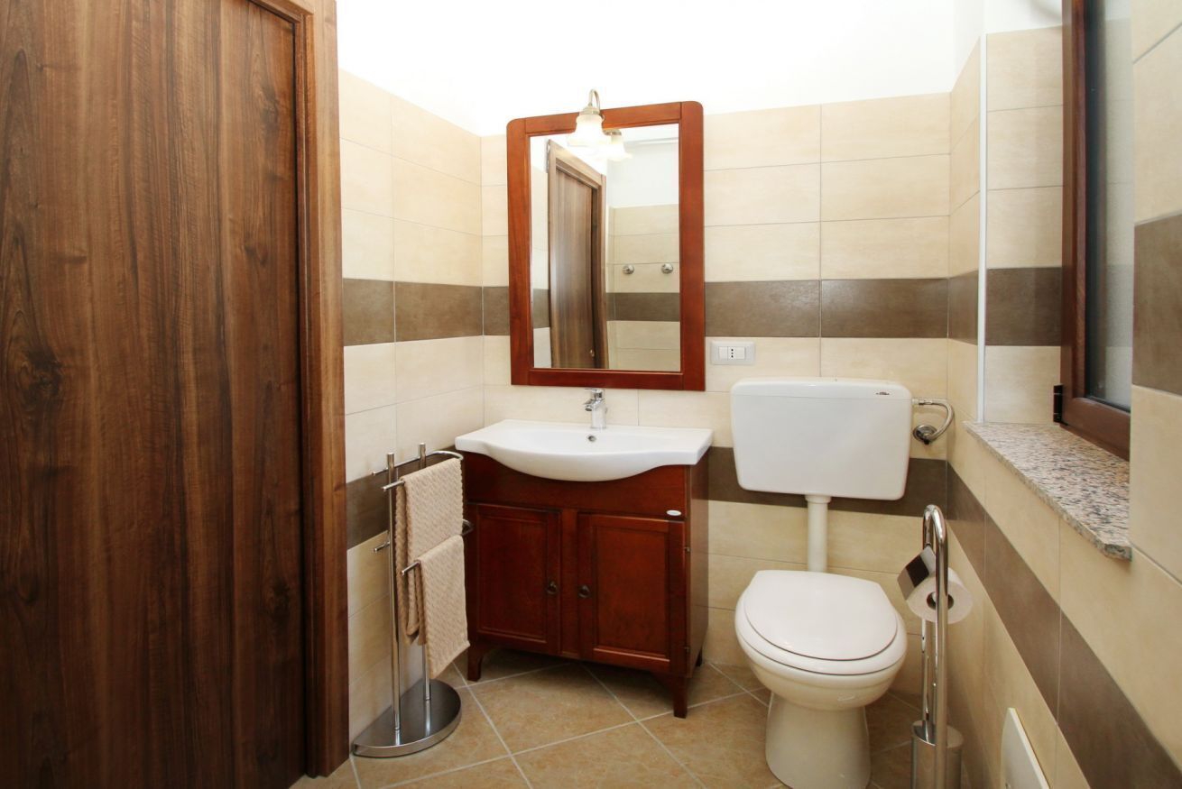 A bathroom with a wooden door, a sink, a toilet, and a mirror.