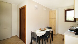 Une cuisine de taille réduite comprenant une table à manger, des chaises et un meuble en bois.
