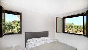 Une chambre à coucher avec un lit, une table de chevet et une fenêtre donnant sur un paysage verdoyant.