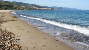 Une plage de galets avec une vue sur des collines lointaines.
