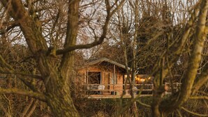 Een houten hutje omringd door bomen.