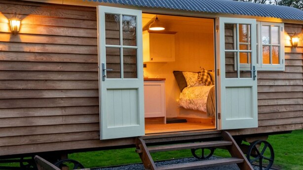 Eine Holzhütte mit einem kleinen Schlafzimmer, einer Küchenzeile und einer Treppe zum Eingang.