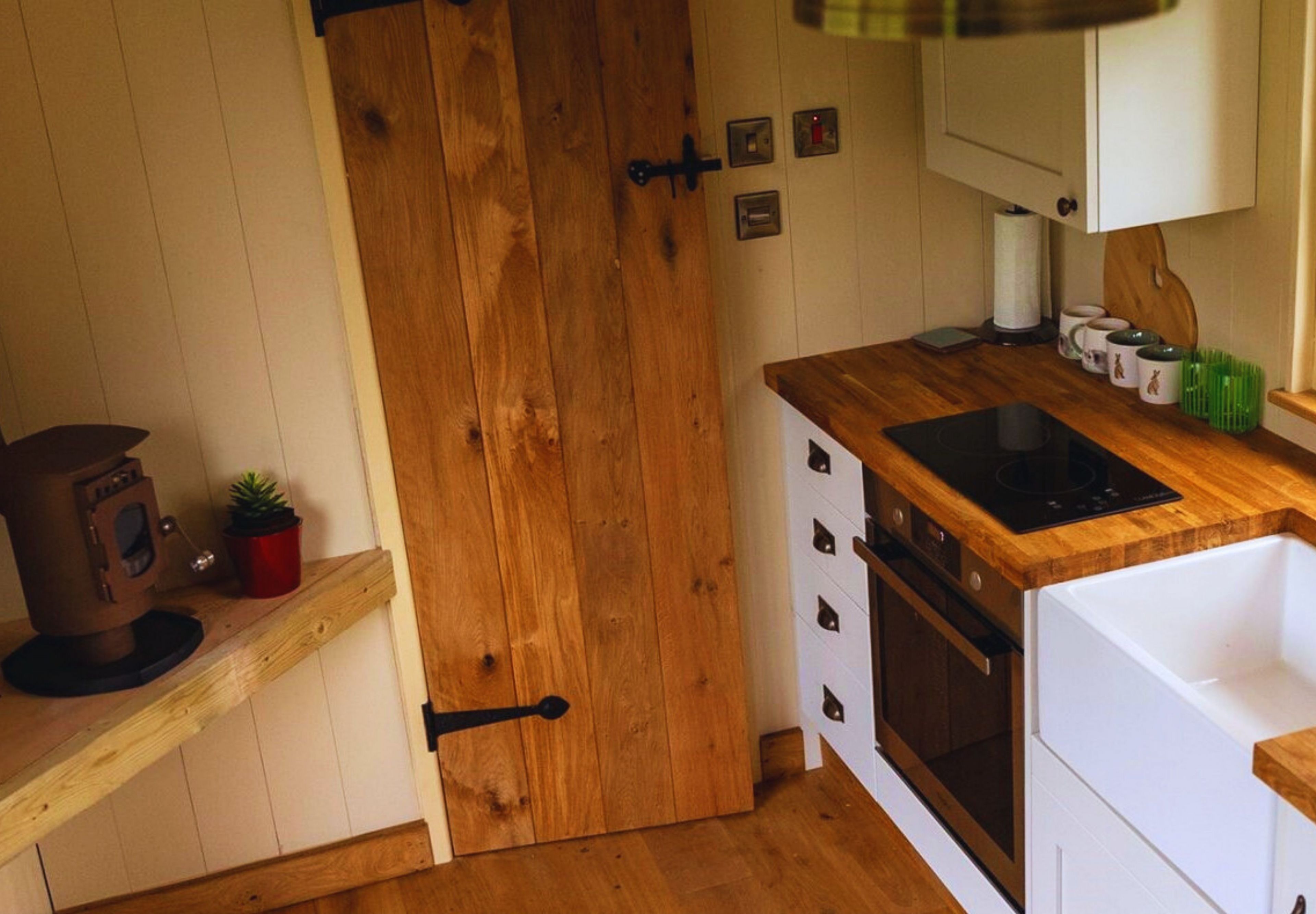 Eine kompakte Küche mit Holzausstattung, einem eingebauten Ofen und einer kleinen Arbeitsfläche.