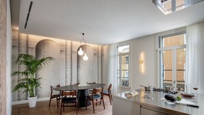 Una cucina moderna con un tavolo da pranzo rotondo, sedie in legno, una pianta in vaso e un'ampia finestra.