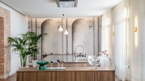 Una cucina moderna con isola centrale, parete in mattoni e una grande finestra.