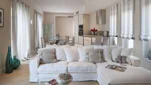 A modern living room with a white sectional sofa, a glass coffee table, and a dining area with a glass table and chairs. - Vila Vita-Vabriga by Villas Guide (Tar)