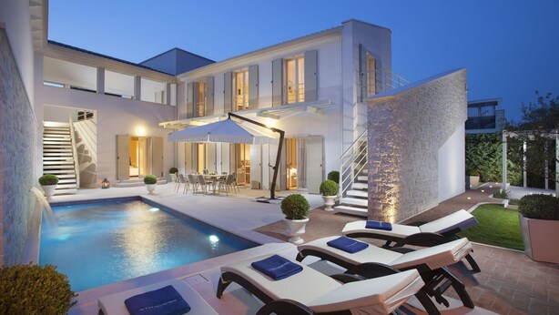 Una casa moderna con piscina, mobiliario exterior y una escalera.