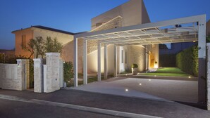 Una casa moderna con entrada porticada, paredes de piedra e iluminación destacada.